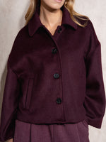 Abrigo de corte corto confeccionado en un tejido estructurado que aporta calidez y una silueta elegante