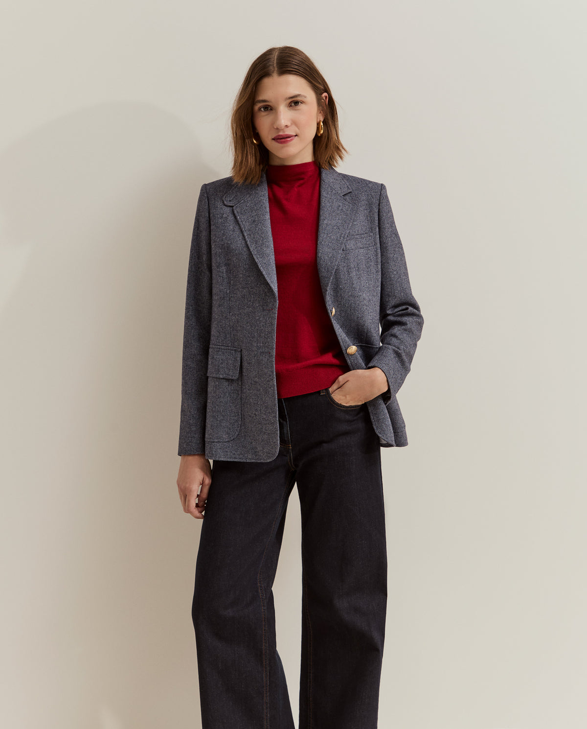 Modelo con blazer de espiga y botones dorados combinada con jersey rojo y vaqueros