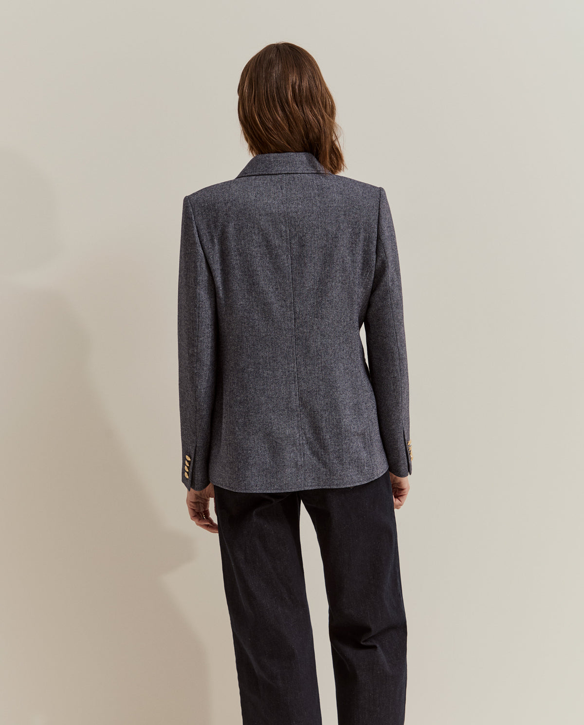 Modelo con blazer de espiga y botones metálicos combinada con jersey rojo y vaqueros