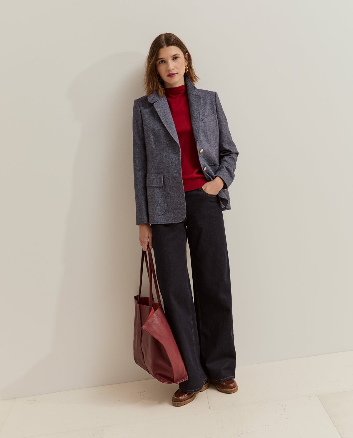 Modelo con blazer de espiga y botones metálicos combinada con jersey rojo y vaqueros