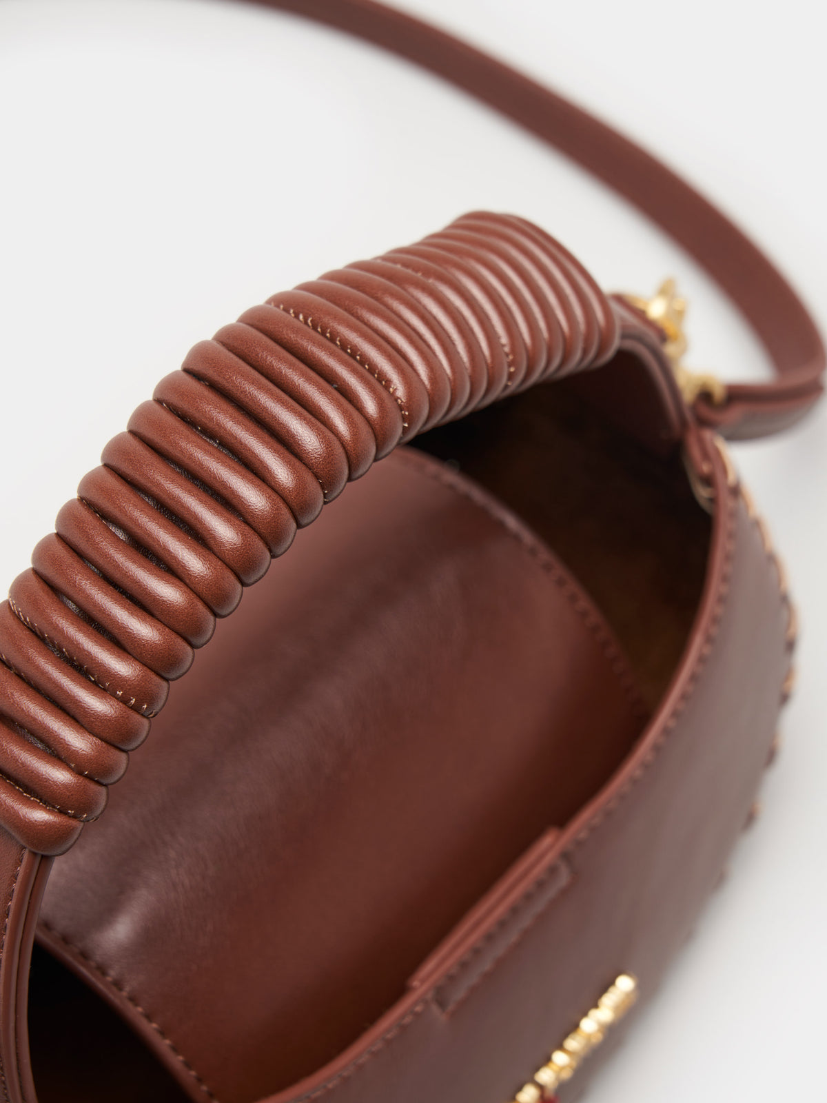 Compacto y lleno de estilo, este mini bolso de mano presenta un diseño estructurado con asa superior esférica y un elegante aplique.
