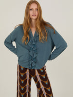 Camisa con volante frontal de manga larga confeccionada en un suave tejido fluido en color azul grisáceo.