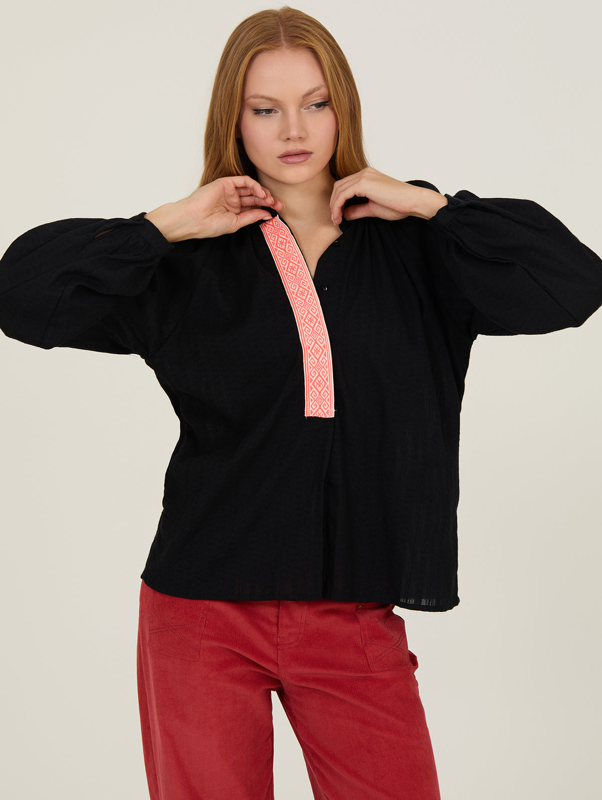 Mujer con camisa negra fluida con detalle flúor en el escote