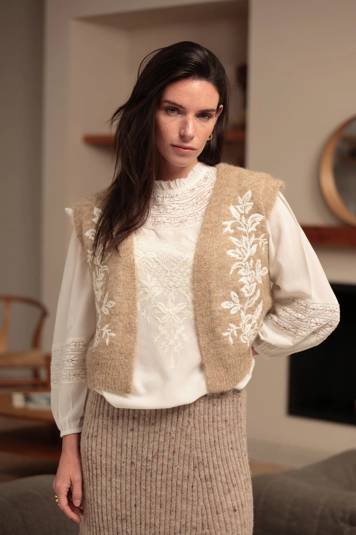 Chaleco de punto beige con bordados florales crudos y bajo acanalado sobre blusa blanca