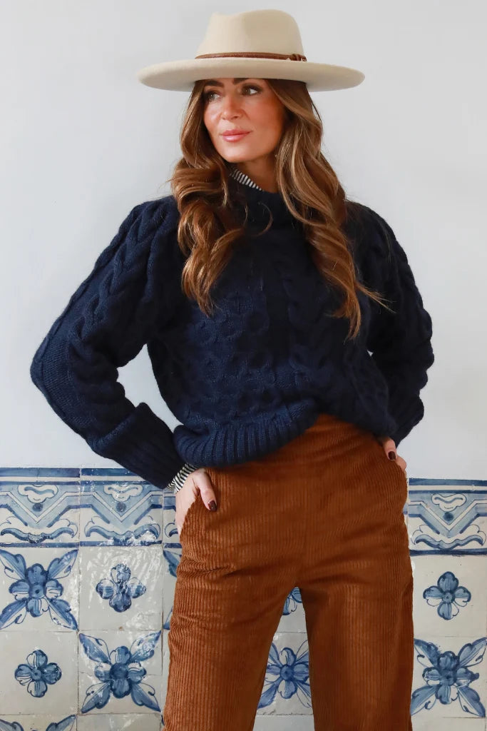 Jersey corto de ochos color vino con cuello subido y mangas abullonadas. Combínalo con el pantalón de pana azul marino de la colección o con vaqueros.