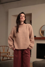 Modelo con jersey rosa empolvado de punto texturizado y ribetes burdeos en cuello y puños