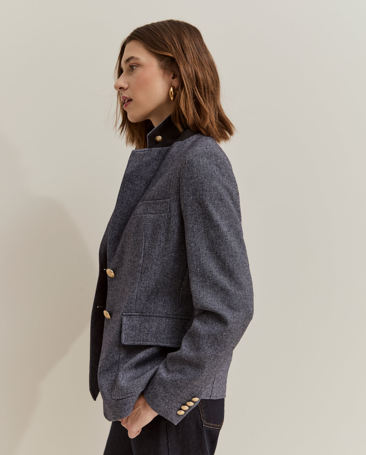 Modelo con blazer de espiga y botones dorados combinada con jersey rojo y vaqueros