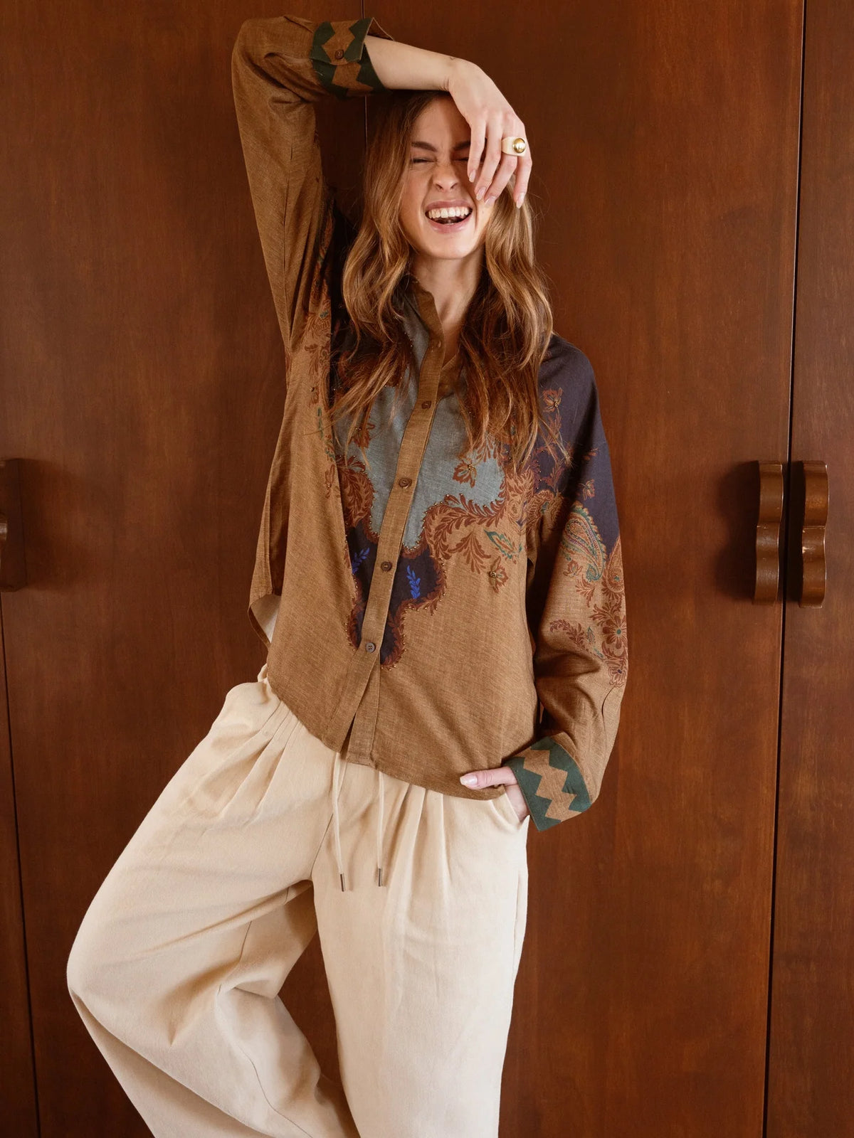 Modelo con camisa de estampado paisley en tonos tierra y puños geométricos en contraste