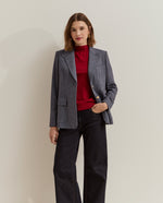 Modelo con blazer de espiga y botones dorados combinada con jersey rojo y vaqueros