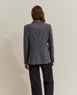 Modelo con blazer de espiga y botones metálicos combinada con jersey rojo y vaqueros