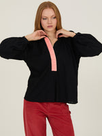 Mujer con camisa negra fluida con detalle flúor en el escote