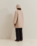 Esta chaqueta acolchada larga de mujer combina un diseño de rombos con un corte holgado, perfecto para llevar sobre tus prendas de punto. 