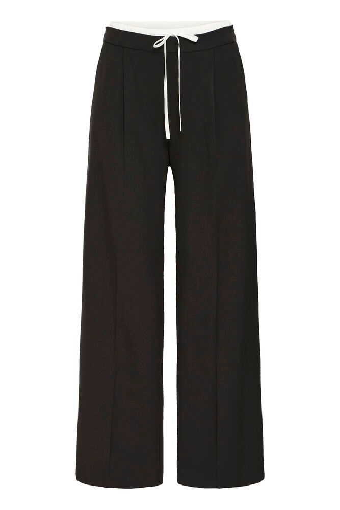 Detalle del cordón fino blanco en la cinturilla del pantalón negro