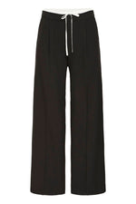 Detalle del cordón fino blanco en la cinturilla del pantalón negro