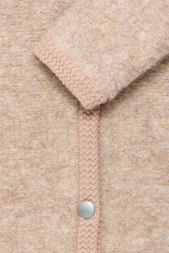 Detalle de los ribetes en contraste de la chaqueta beige clara