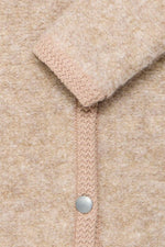 Detalle de los ribetes en contraste de la chaqueta beige clara