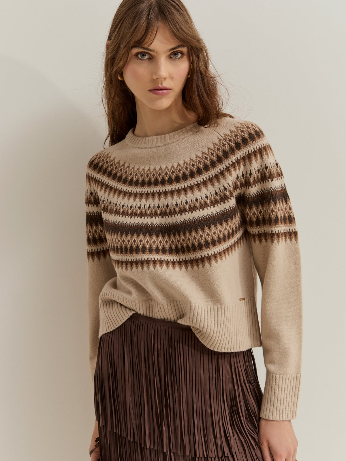Jersey de punto con 80% lana y estampado geométrico nórdico. Diseño de manga larga, cuello redondo y acabados acanalados, ideal para el invierno.