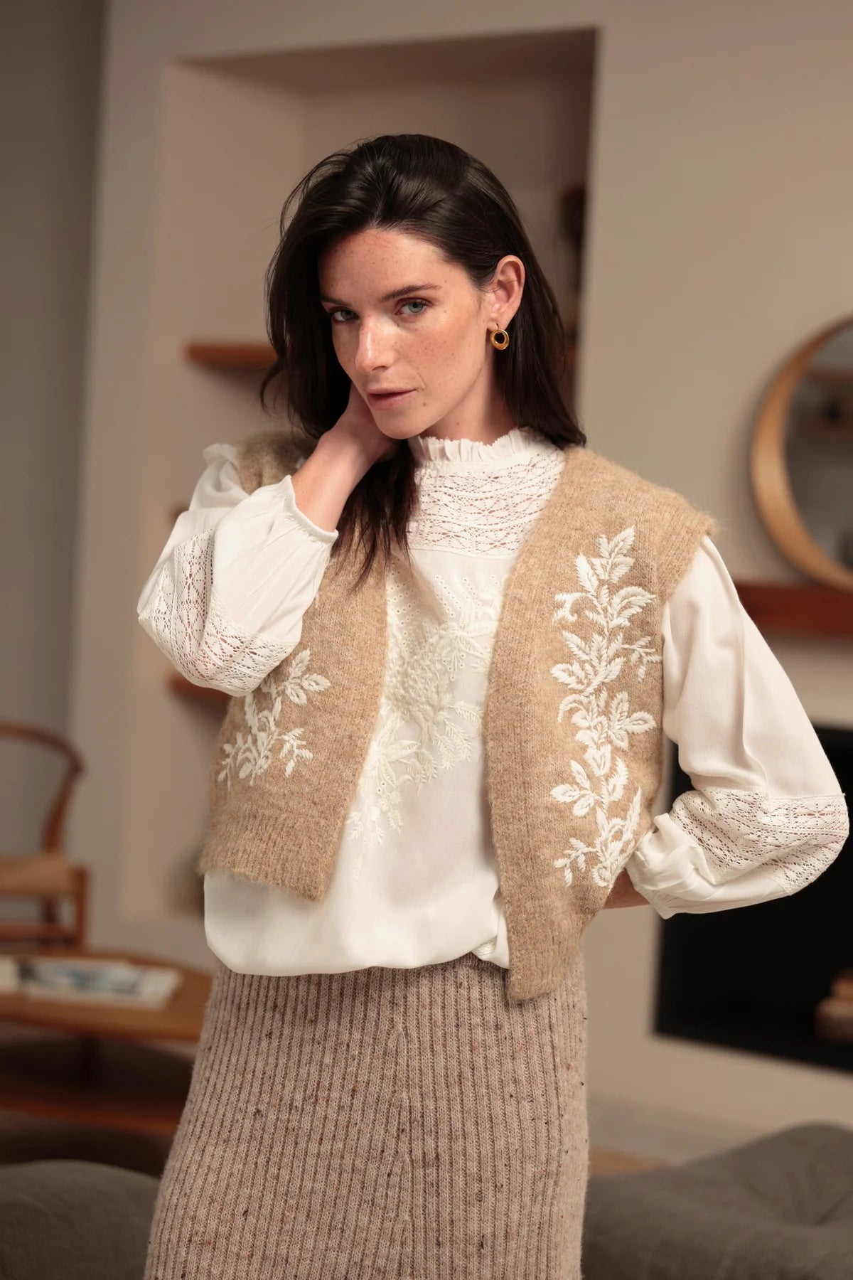 Modelo con chaleco abierto de punto beige y bordados florales en la parte delantera
