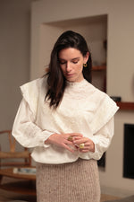 Blusa cruda con bordados florales, cenefas de encaje y mangas abullonadas sobre modelo